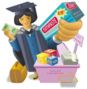 The Pioneer magazine cover from Spring 2003. A person in graduation attire stands at a sales counter, holding a large box labeled 'TOOTHPASTE – NEW! MINTY FRESH' in one hand and paper currency with a pound (£) symbol in the other. The counter displays a 'PAY HERE' sign, a cash register, colorful product boxes, and a shopping basket. A brown bag labeled 'SAMPLES' sits on the floor. The scene humorously blends academic achievement with commercial activity, suggesting themes of education, marketing, and consumerism.